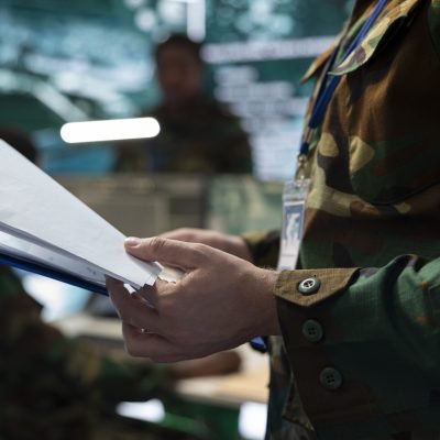 Trooper analyzes federal case file for a new national safety mission, studying defense tactics and objectives before briefing the recruits. Army specialist making attack plans to ensure success.